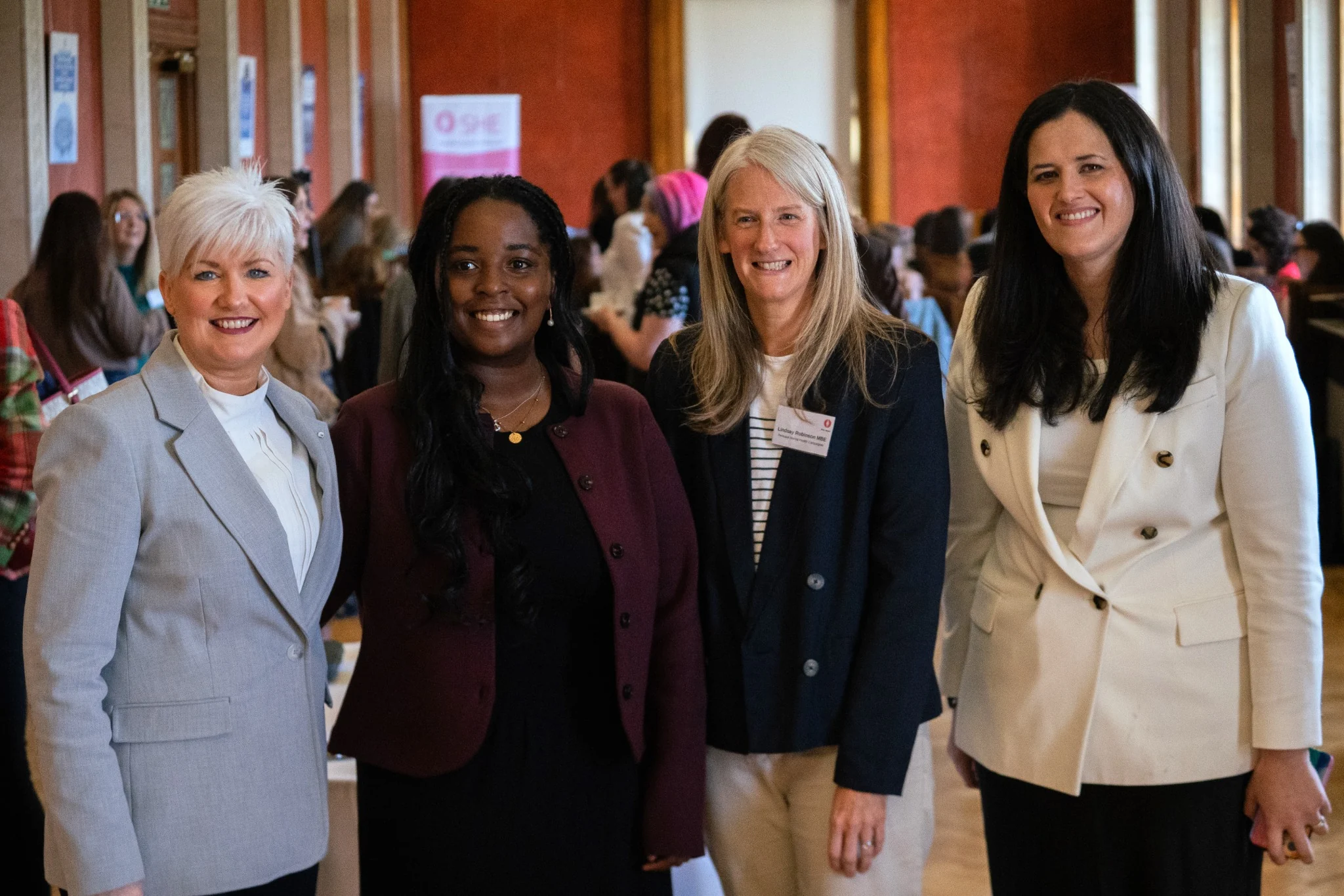 Four attendees smiling together at the SHE Women’s Health Forum in the Long Gallery